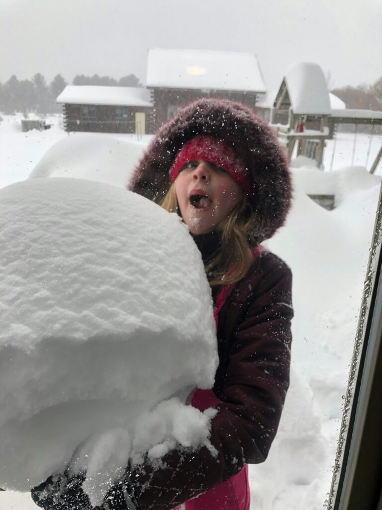 Child with mouth open about to eat a snowball