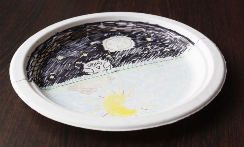 Paper plate divided in half, with night illustrated on one half and day on the other