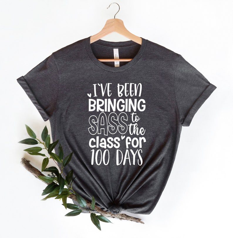 A simple gray shirt has white lettering that says I've been bringing sass to the class for 100 days.