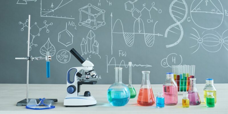 Interior of modern chemistry classroom: desk with microscope and laboratory glassware, blackboard - Science Resources for Middle and High School