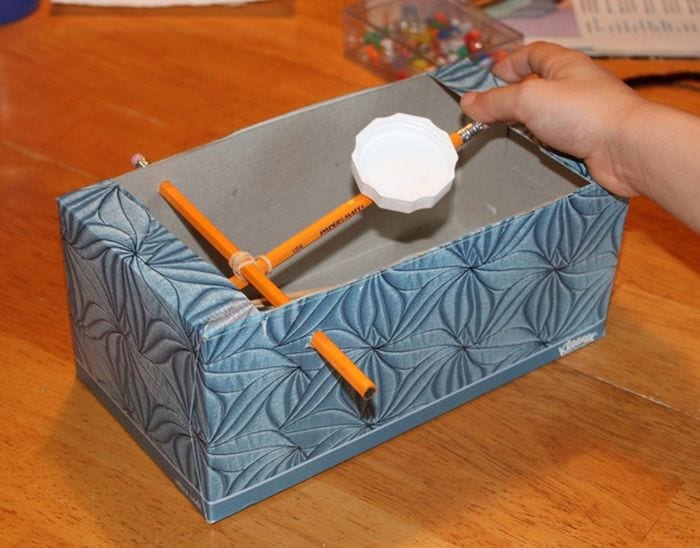 Tissue box modified with pencils and rubber bands to create a toy catapult